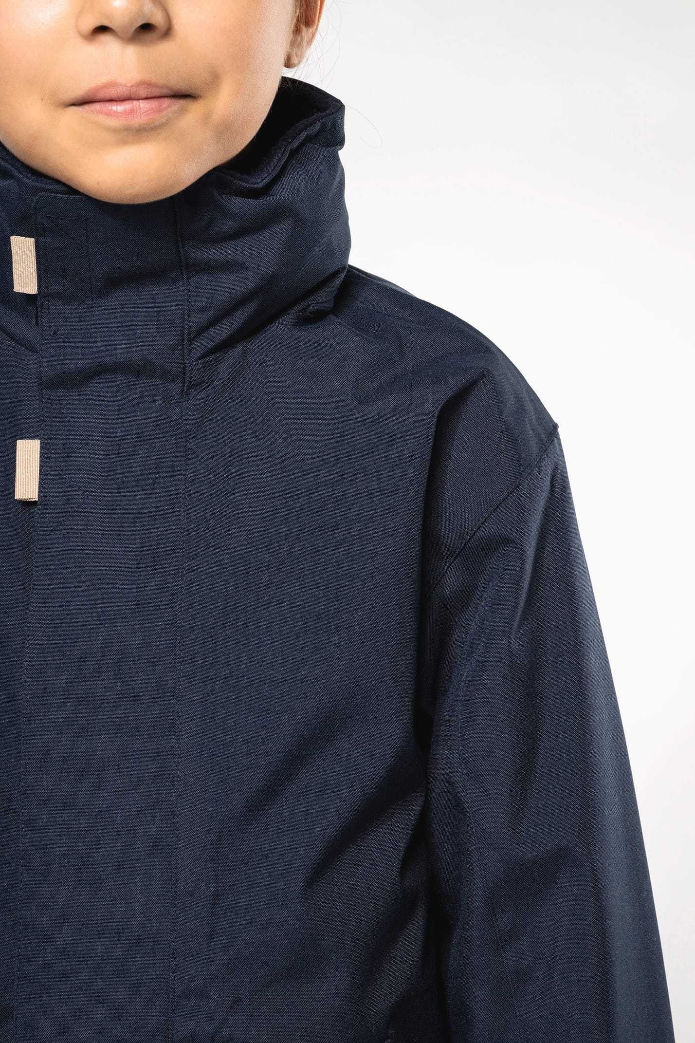 Jeune fille brune cheveux attachés qui porte une parka Navy.