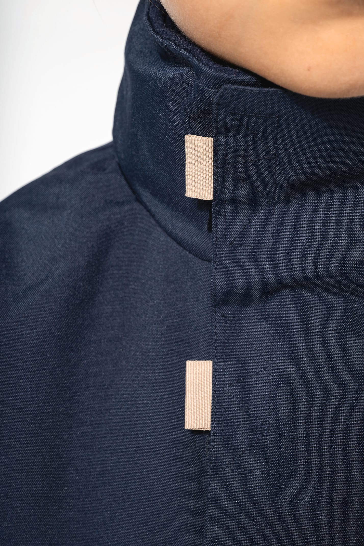 Jeune fille brune cheveux attachés qui porte une parka Navy.