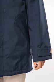 Jeune fille brune cheveux attachés qui porte une parka Navy.