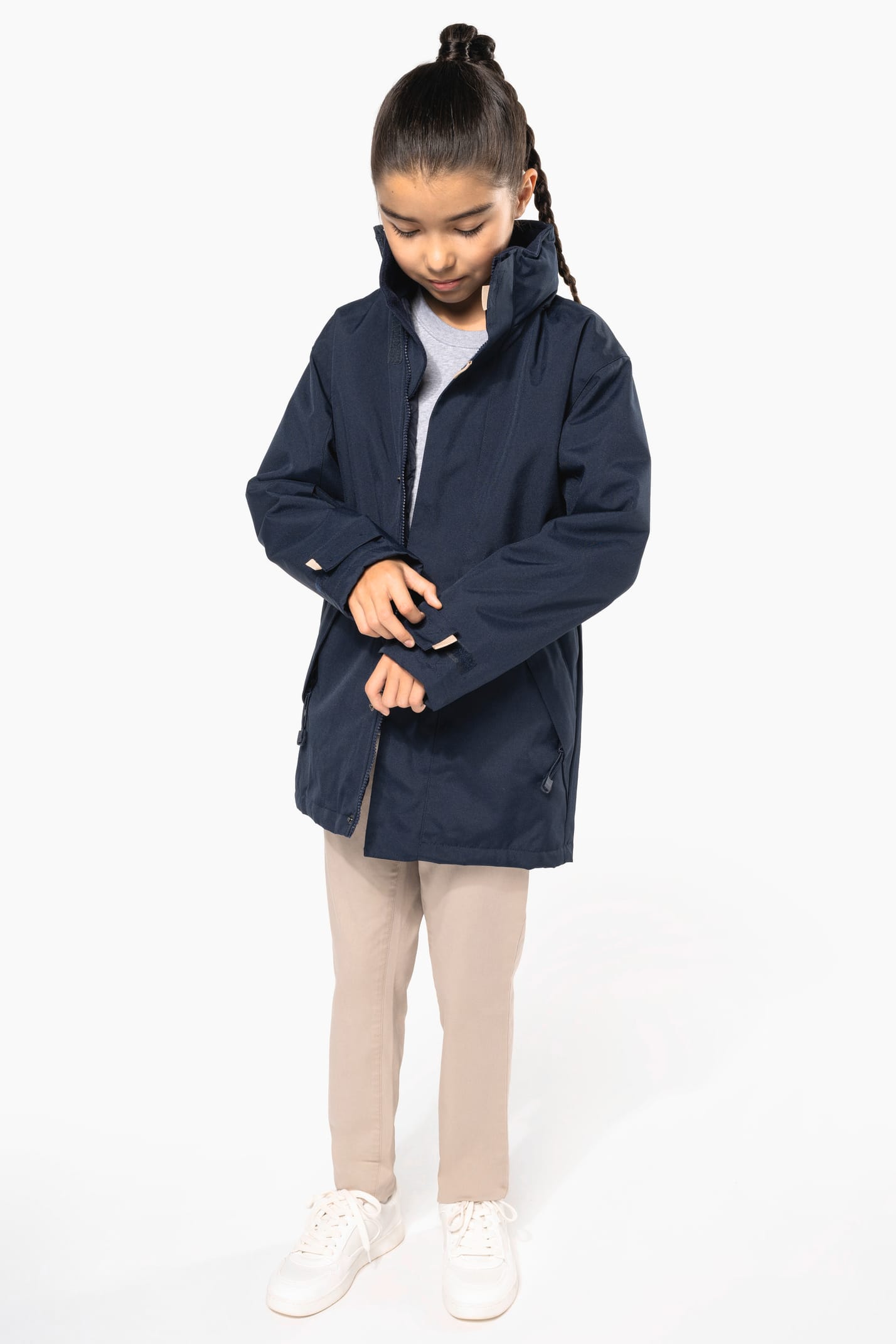 Jeune fille brune cheveux attachés qui porte une parka Navy.