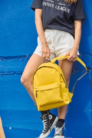 Jeune femme qui porte un sac à dos classique jaune.