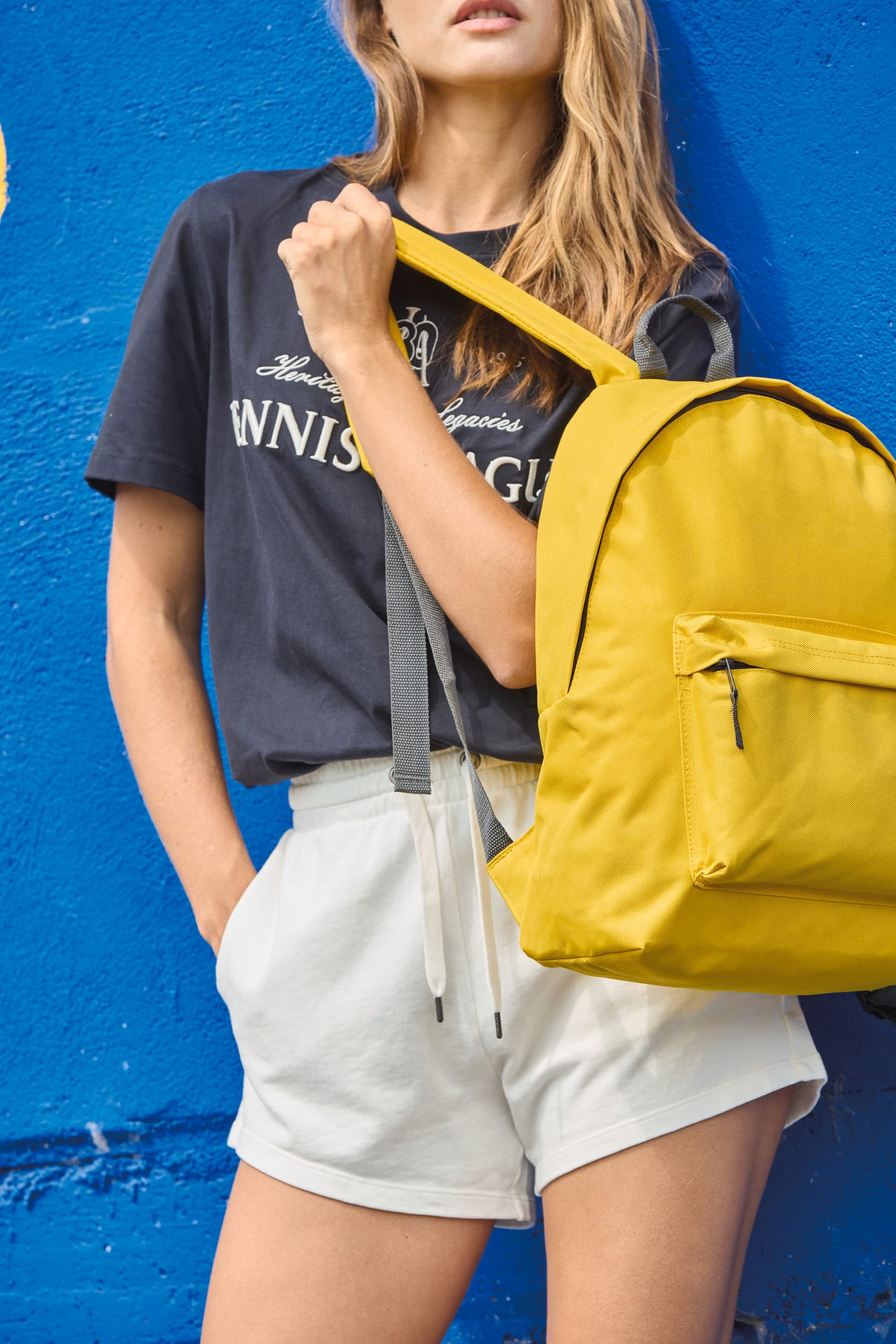 Jeune femme qui porte un sac à dos classique jaune.