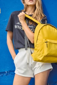 Jeune femme qui porte un sac à dos classique jaune.