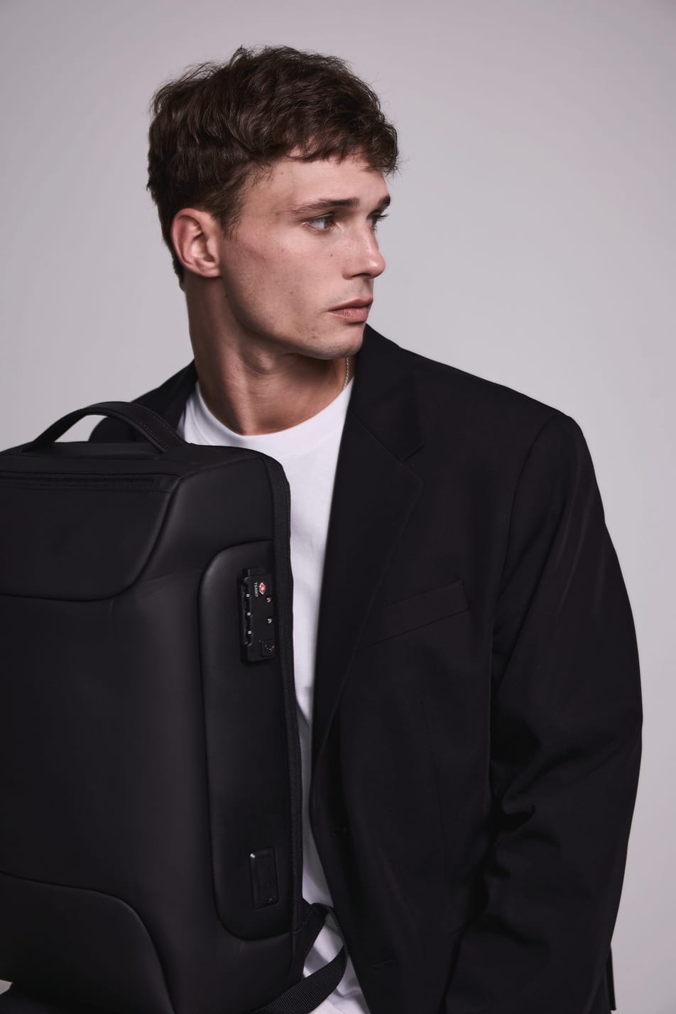 Homme brun veste noir avec sac à dos business noir. Effet flou.