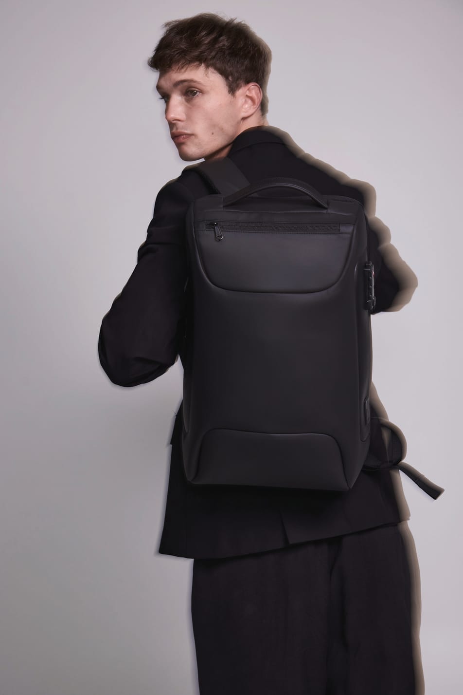 Homme brun veste noir avec sac à dos business noir. Effet flou.