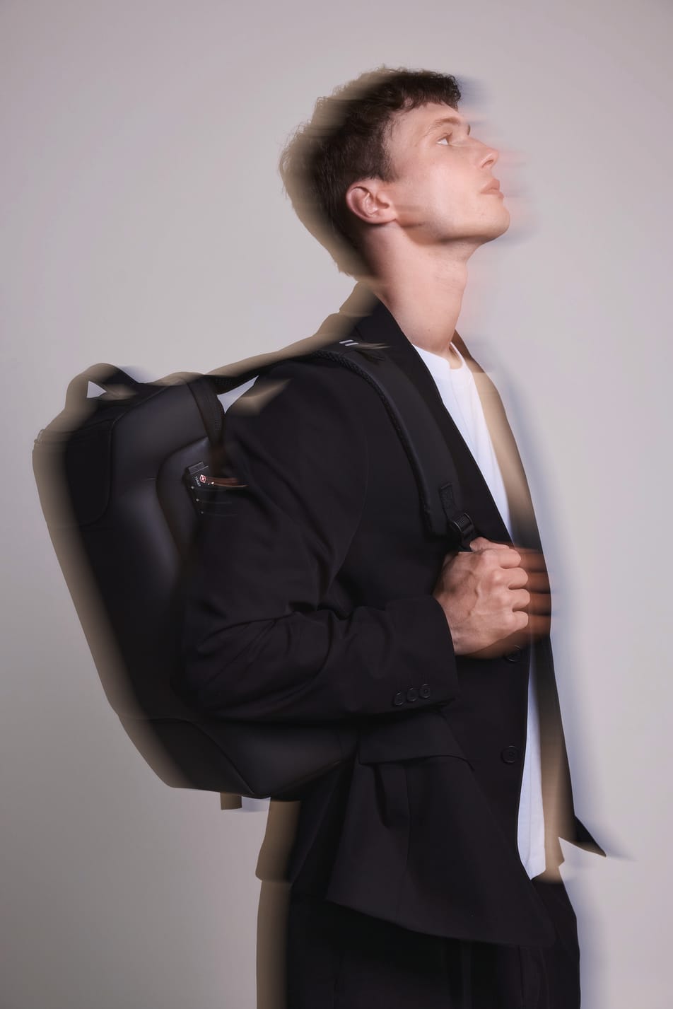 Homme brun veste noir avec sac à dos business noir. Effet flou.