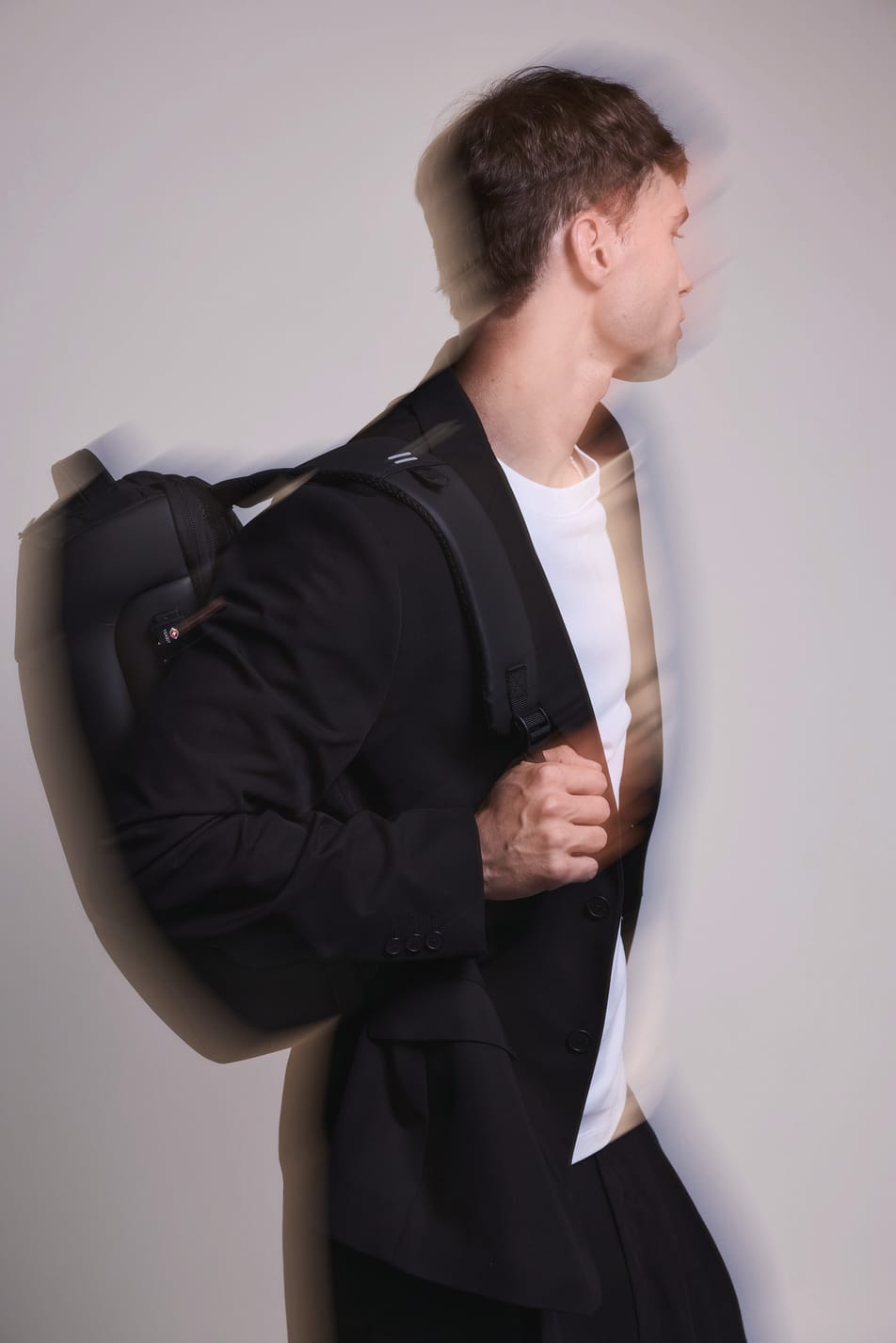 Homme brun veste noir avec sac à dos business noir. Effet flou.