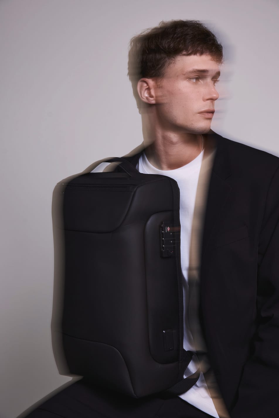 Homme brun veste noir avec sac à dos business noir. Effet flou.
