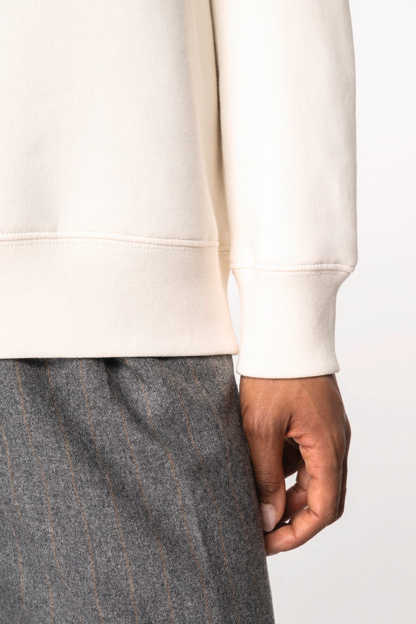 Détail d'une manche d'un sweat-shirt à col polo zippé blanc porté par une femme 