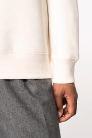 Détail d'une manche d'un sweat-shirt à col polo zippé blanc porté par une femme 