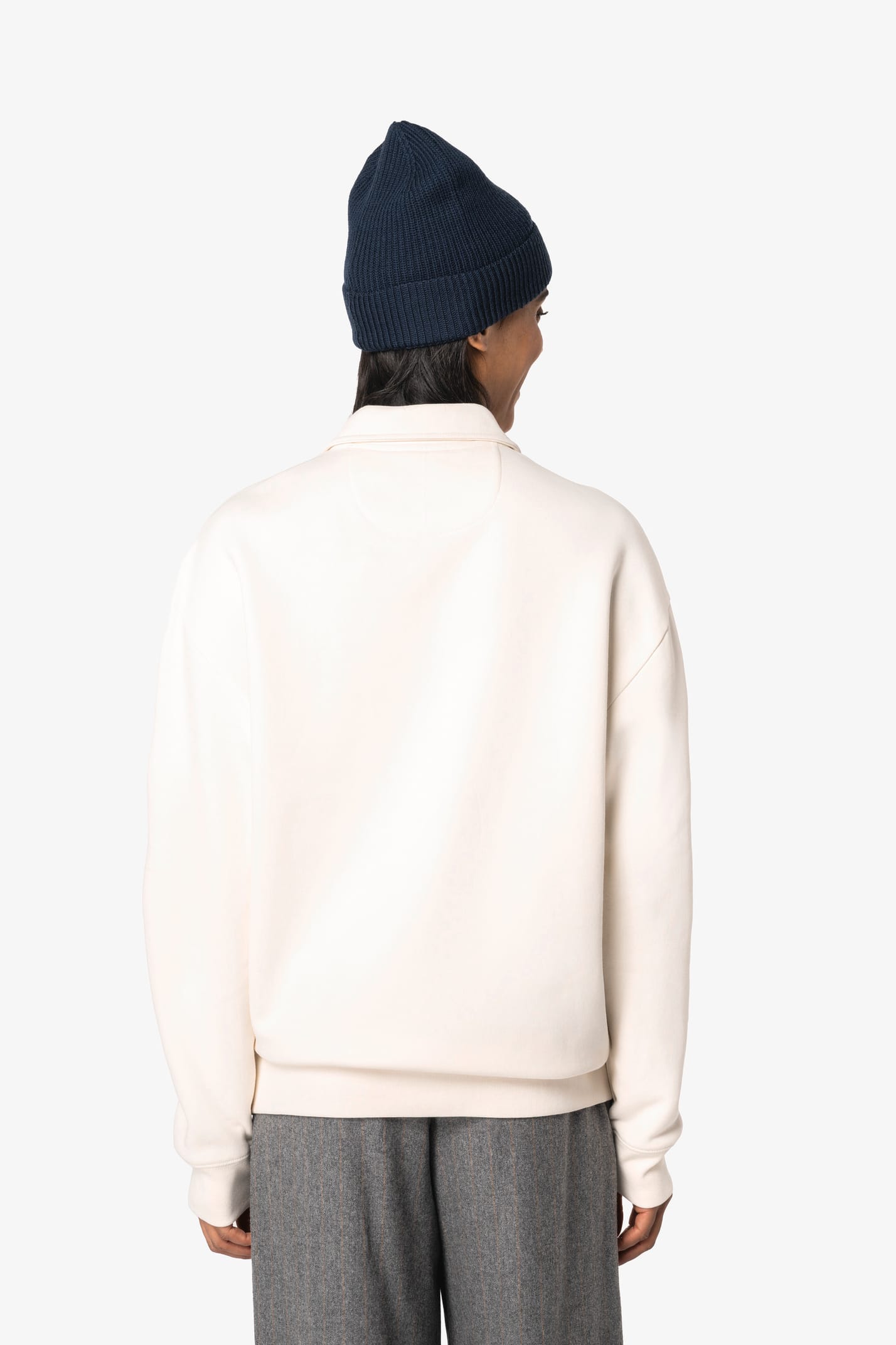 Sweat-shirt à col polo zippé blanc porté par une femme de dos