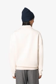 Sweat-shirt à col polo zippé blanc porté par une femme de dos