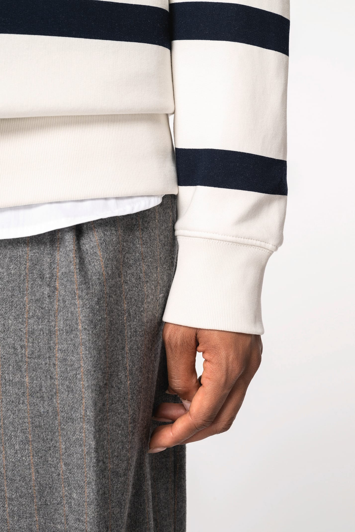 Détail d'une manche d'un sweat-shirt rayé blanc et noir porté par une femme