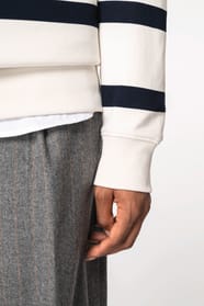 Détail d'une manche d'un sweat-shirt rayé blanc et noir porté par une femme