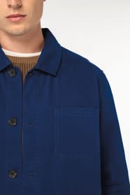 Détail d'une surchemise bleu portée par un homme