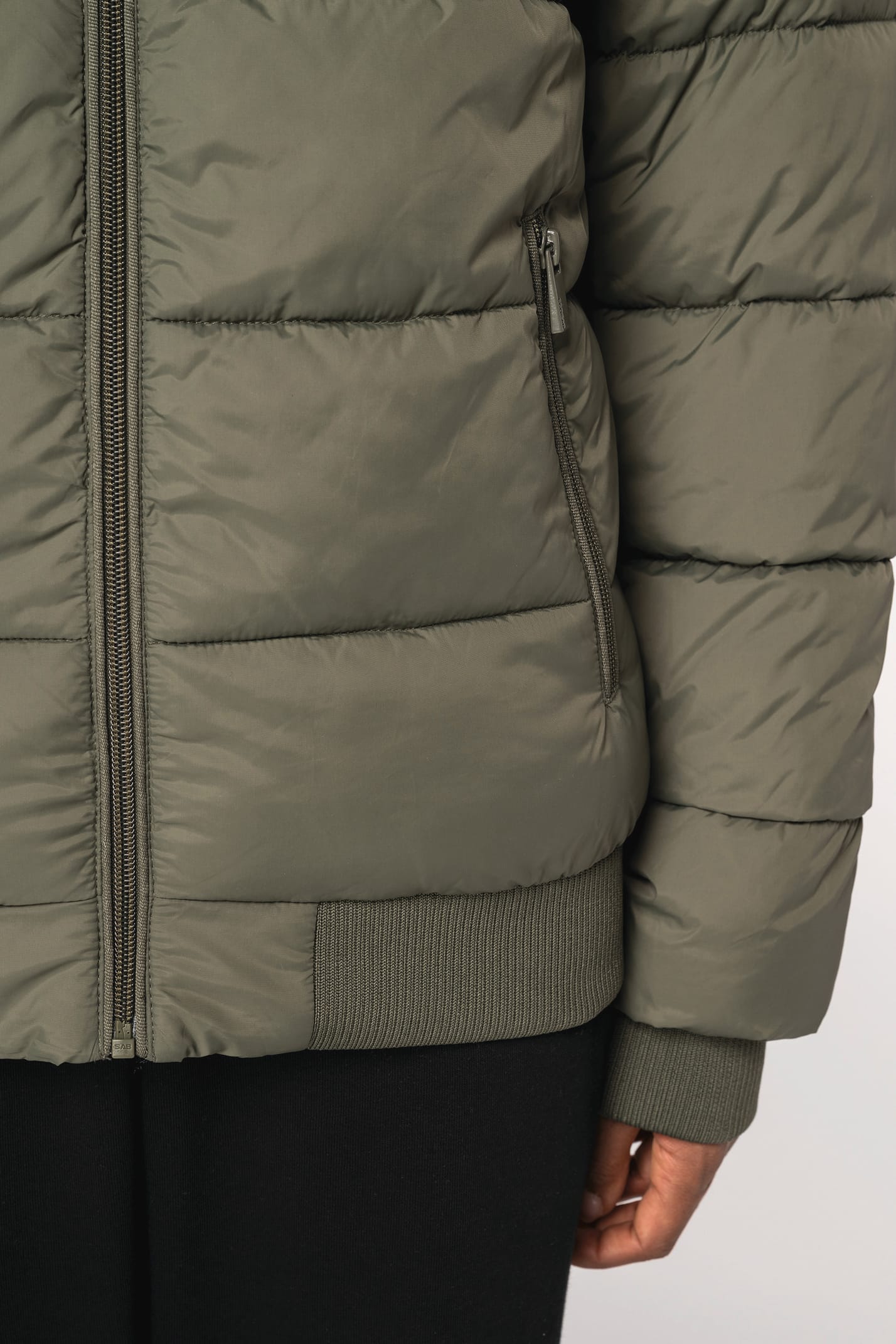 Détail poche d'une doudoune kaki à col teddy porté par une femme