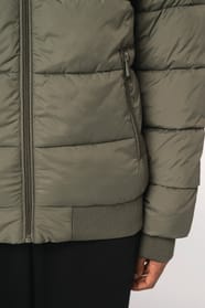 Détail poche d'une doudoune kaki à col teddy porté par une femme