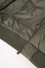 Détail poche d'une doudoune kaki à col teddy porté par une femme