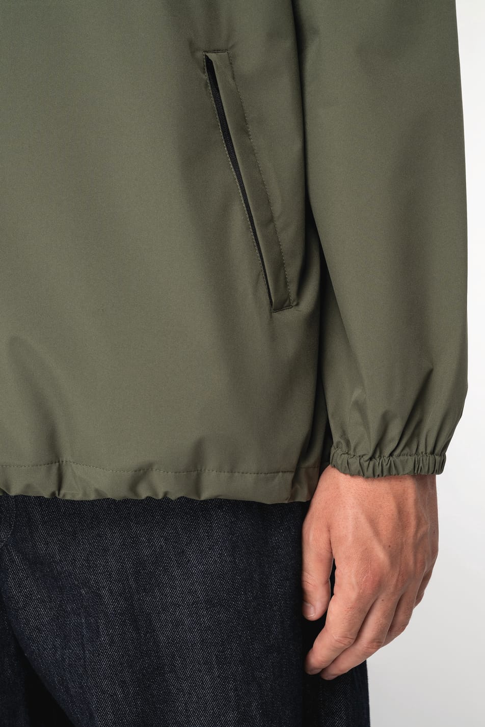 Détail d'une veste coupe-vent quart zip kaki portée par un homme