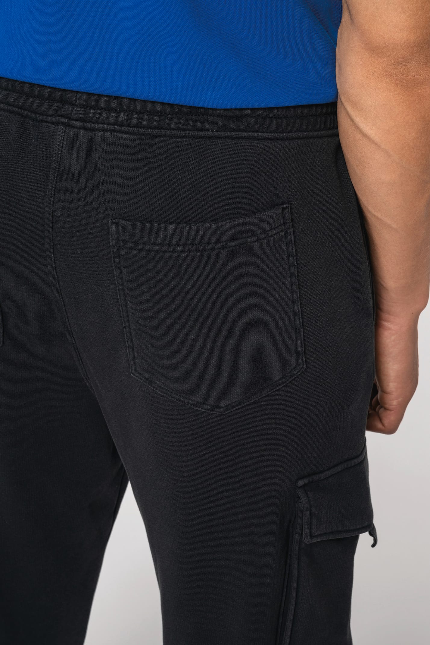 Détail de la poche arrière d'un pantalon cargo noir porté par un homme