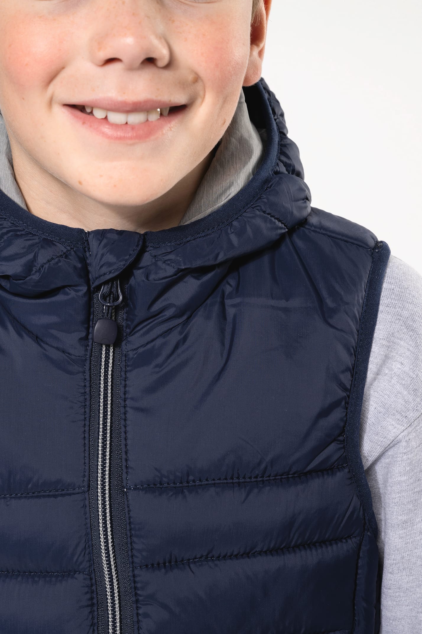 Jeune garçon châtain qui porte un bodywarmer à capuche Navy.
