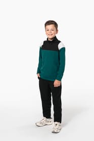 Jeune garçon qui porte une veste de survêtement zippée tricolore : verte, noire et blanche.