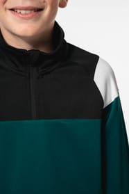 Jeune garçon qui porte une veste de survêtement zippée tricolore : verte, noire et blanche.