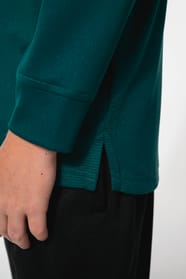 Jeune garçon qui porte une veste de survêtement zippée tricolore : verte, noire et blanche.