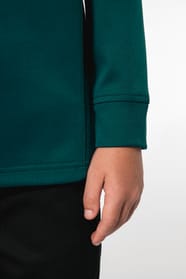 Jeune garçon qui porte une veste de survêtement zippée tricolore : verte, noire et blanche.