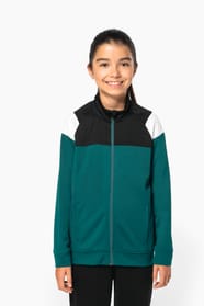 Jeune fille brune cheveux attachés qui porte une veste de survêtement zippée tricolore tendance et personnalisable : verte, noire et blanche.
