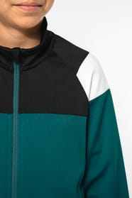 Jeune fille brune cheveux attachés qui porte une veste de survêtement zippée tricolore tendance et personnalisable : verte, noire et blanche.