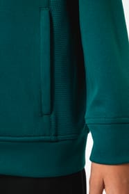 Jeune fille brune cheveux attachés qui porte une veste de survêtement zippée tricolore tendance et personnalisable : verte, noire et blanche.