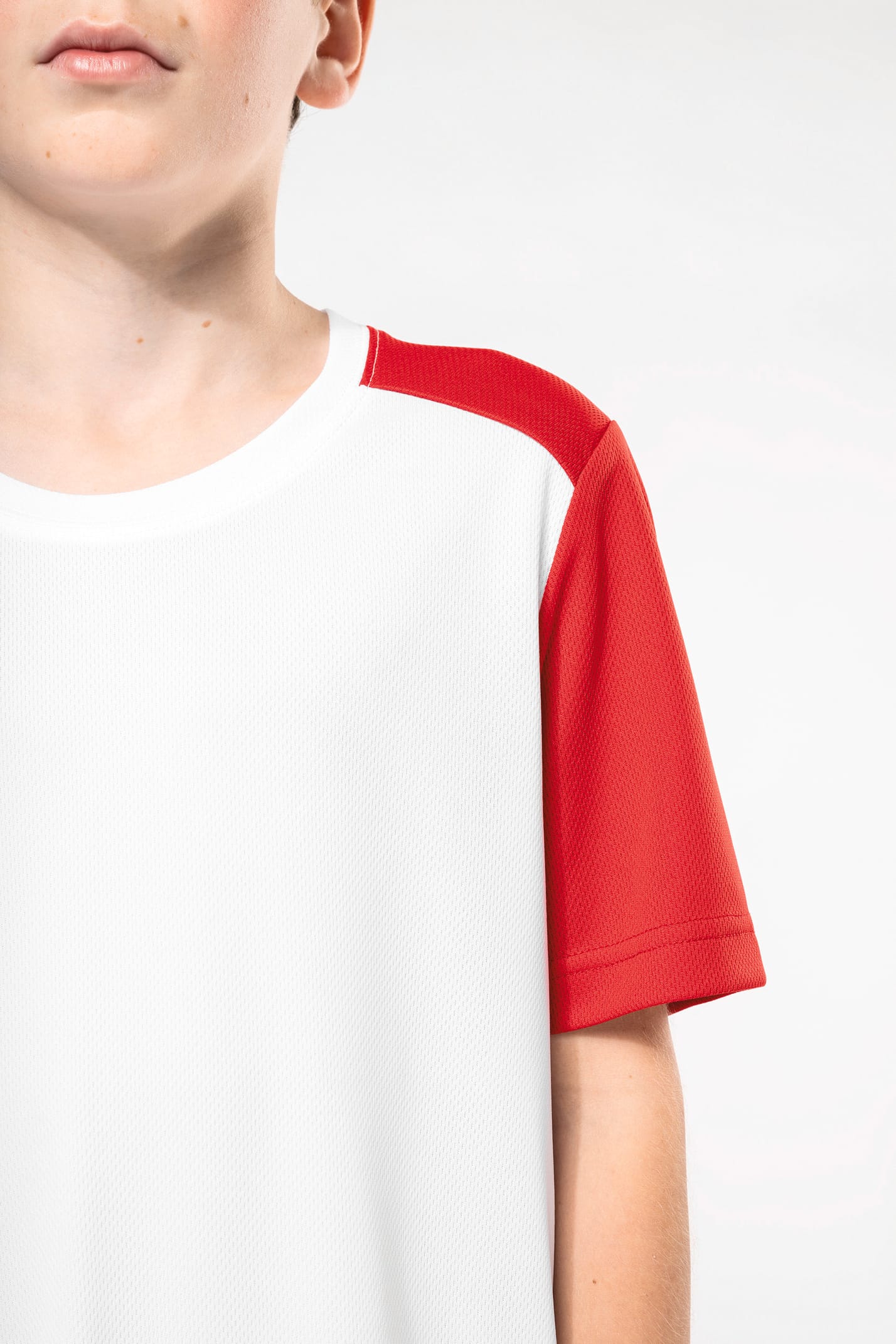 Jeune garçon cheveux courts châtain qui porte un t-shirt de sport bicolore White et Red.