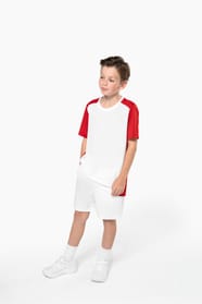 Jeune garçon châtain cheveux courts qui porte un t-shirt bicolore et un short de sport.