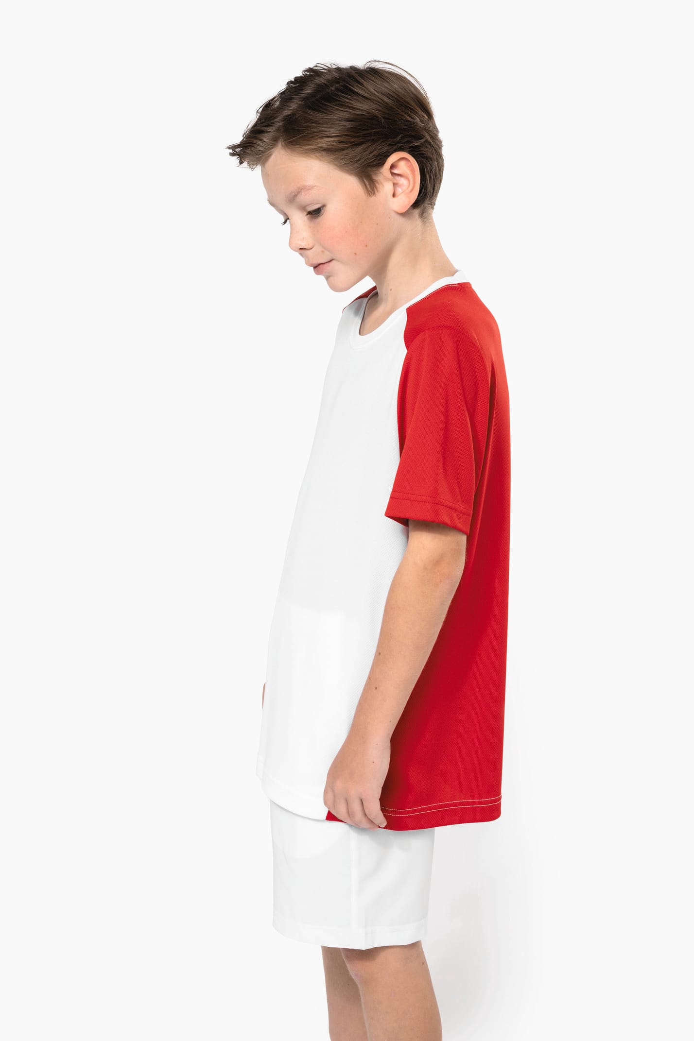 Jeune garçon châtain cheveux courts qui porte un t-shirt bicolore et un short de sport.