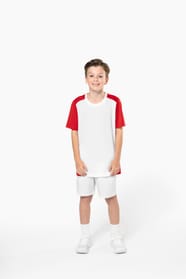 Jeune garçon châtain cheveux courts qui porte un t-shirt bicolore et un short de sport.