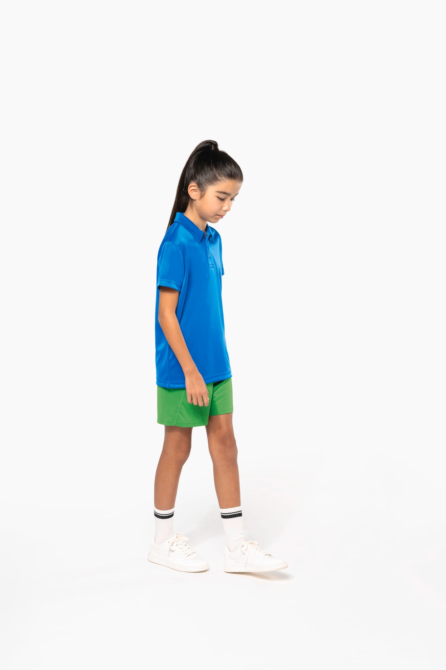Fillette brune cheveux attachés qui porte un polo sport manches courtes Aqua Blue.