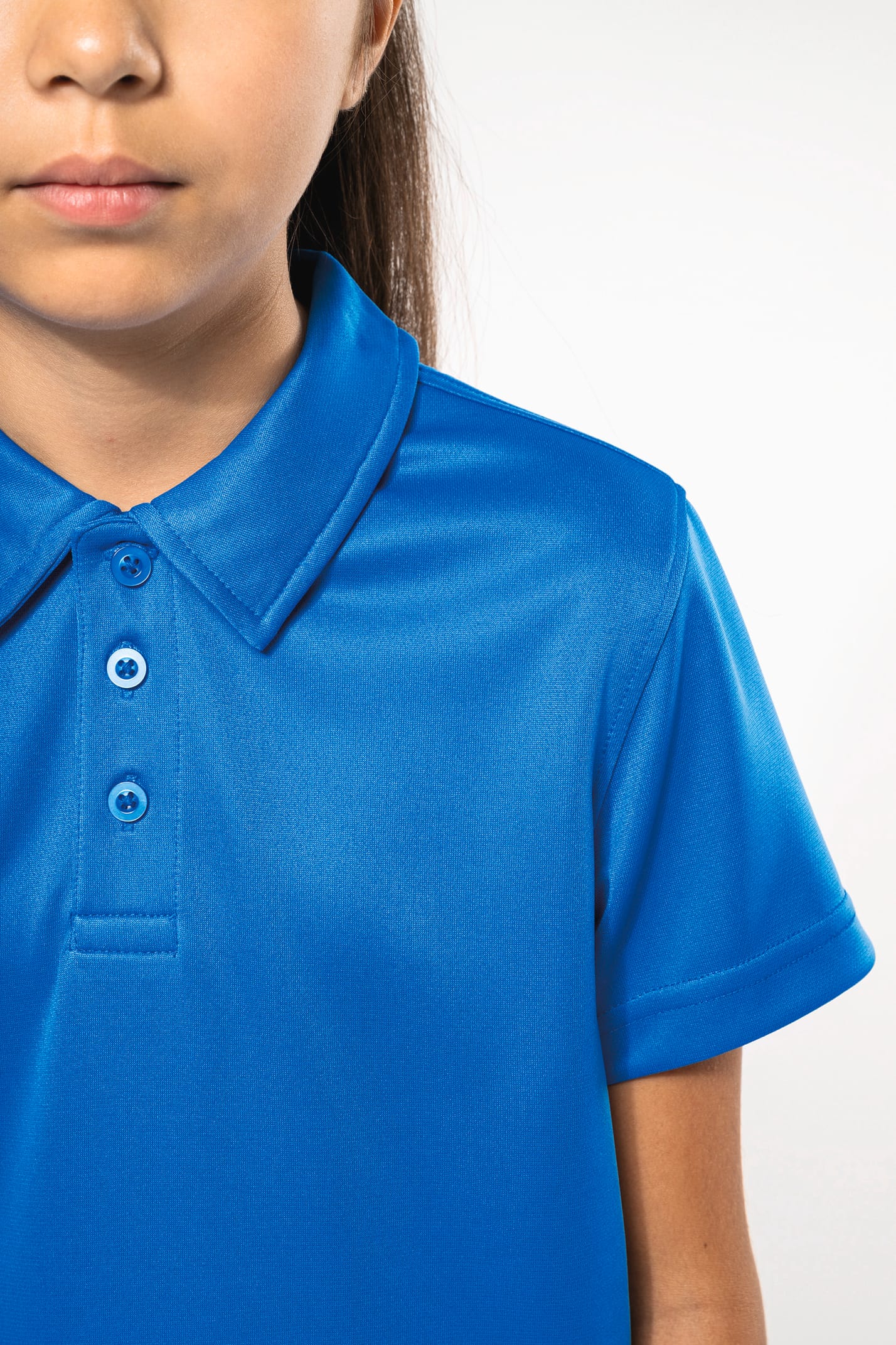Fillette brune cheveux attachés qui porte un polo sport manches courtes Aqua Blue.
