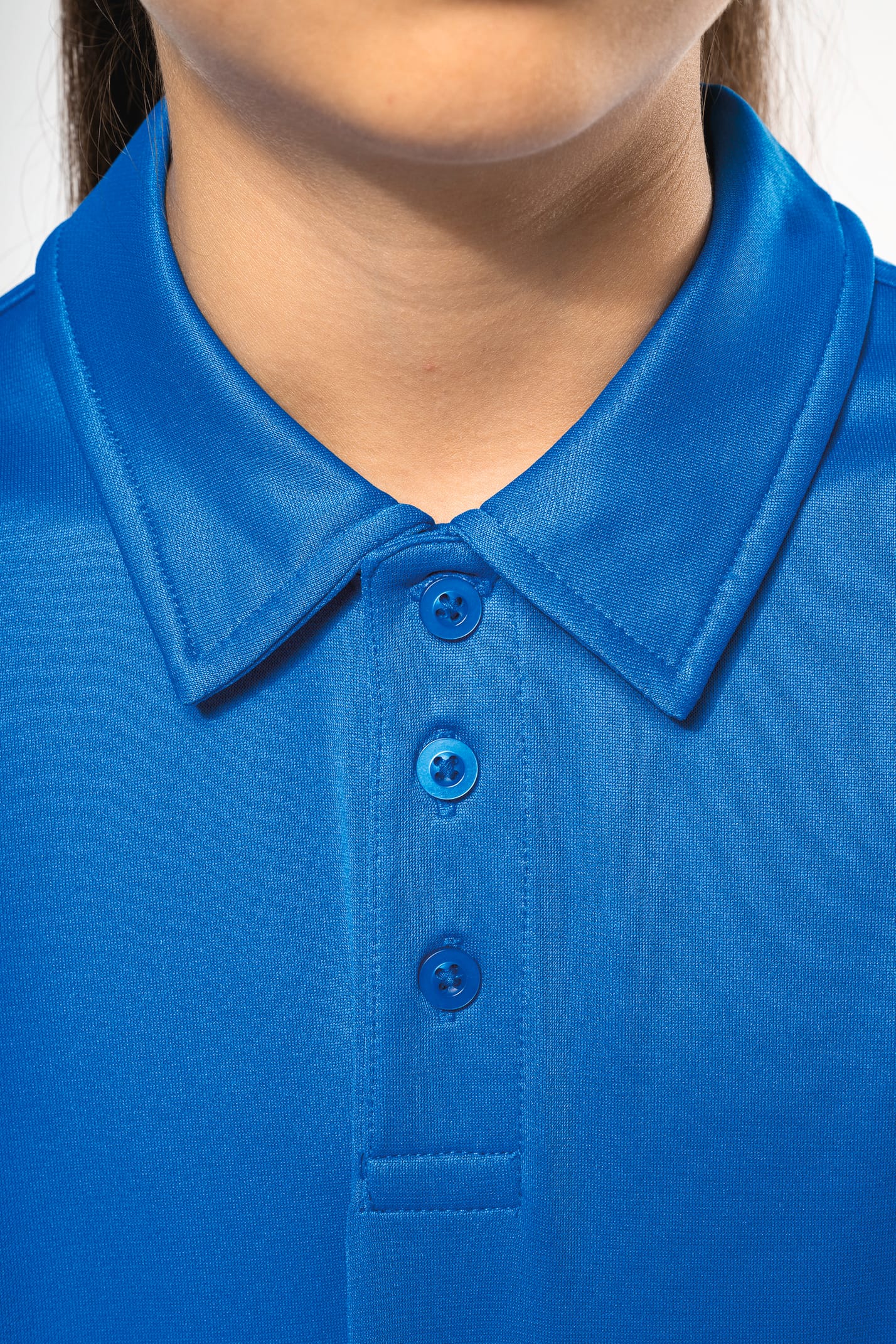 Fillette brune cheveux attachés qui porte un polo sport manches courtes Aqua Blue.
