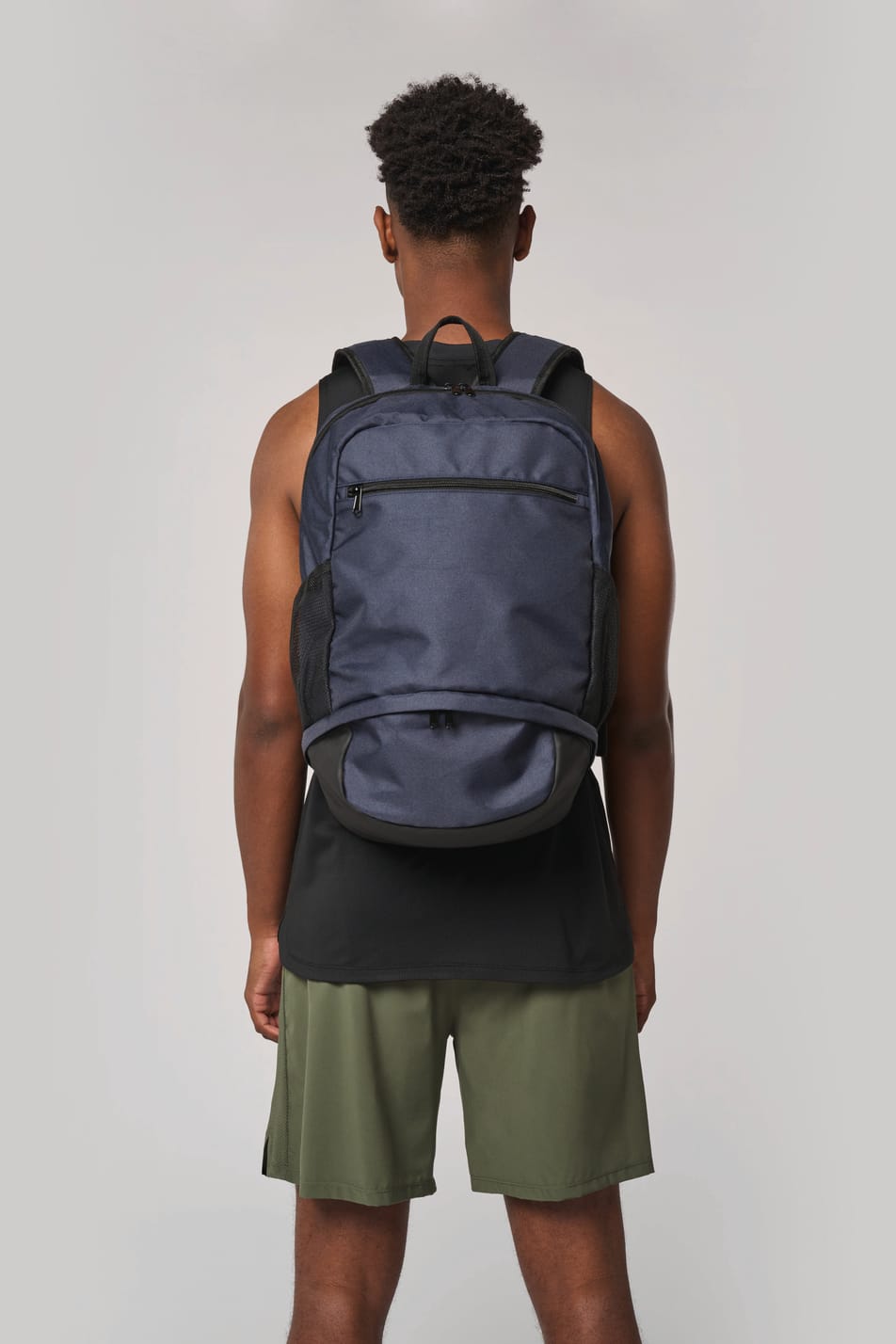 Homme portant un sac à dos bleu foncé avec compartiment pour ballon.