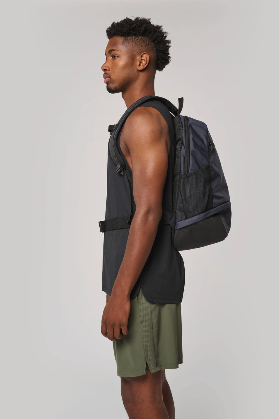 Homme portant un sac à dos bleu foncé avec compartiment pour ballon.