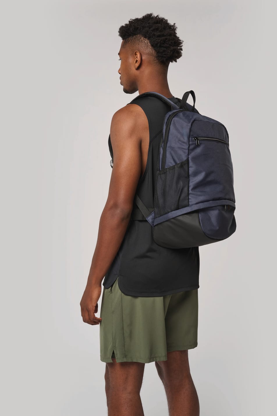 Homme portant un sac à dos bleu foncé avec compartiment pour ballon.