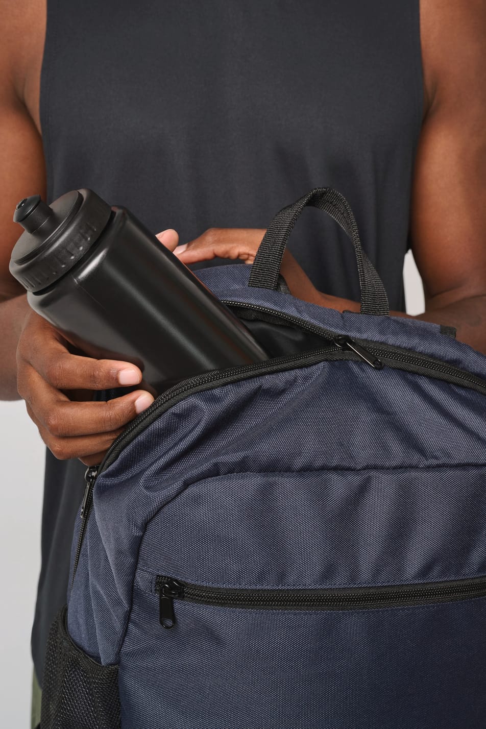 Homme portant un sac à dos bleu foncé avec compartiment pour ballon.
