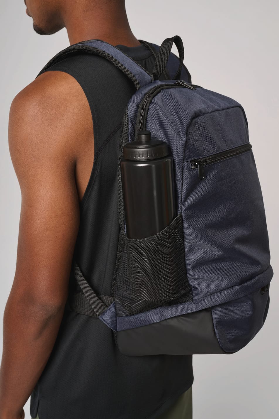 Homme portant un sac à dos bleu foncé avec compartiment pour ballon.