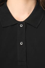 Jeune femme aux cheveux châtains longs et légèrement ondulés, portant un polo noir en coton Supima® à manches courtes, sobre et élégant. Sa fibre extra-longue offre résistance et douceur, idéale pour le marquage textile. Elle complète sa tenue avec un pan