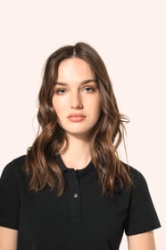 Jeune femme aux cheveux châtains longs et légèrement ondulés, portant un polo noir en coton Supima® à manches courtes, sobre et élégant. Sa fibre extra-longue offre résistance et douceur, idéale pour le marquage textile. Elle complète sa tenue avec un pan