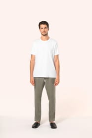 Jeune homme aux cheveux châtains courts portant un T-shirt blanc en coton Supima® col rond à manches courtes, 180 g/m². Sa coupe droite, sa construction coupée-cousue et ses finitions soignées mettent en valeur un jersey de grande finesse, au toucher doux