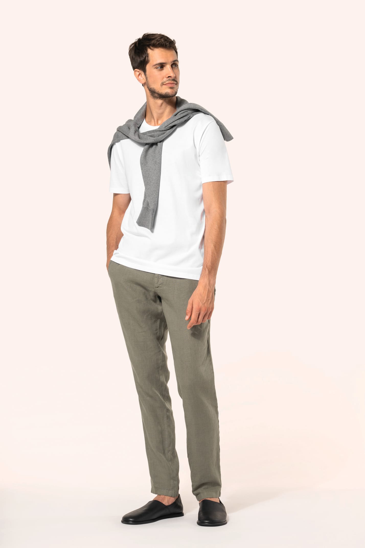 Jeune homme aux cheveux châtains courts portant un T-shirt blanc en coton Supima® col rond à manches courtes, 180 g/m². Sa coupe droite, sa construction coupée-cousue et ses finitions soignées mettent en valeur un jersey de grande finesse, au toucher doux