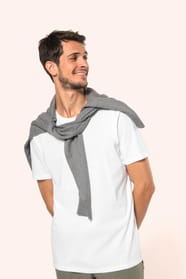 Jeune homme aux cheveux châtains courts portant un T-shirt blanc en coton Supima® col rond à manches courtes, 180 g/m². Sa coupe droite, sa construction coupée-cousue et ses finitions soignées mettent en valeur un jersey de grande finesse, au toucher doux