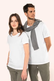 Jeune femme aux cheveux châtains longs et légèrement ondulés et jeune homme aux cheveux châtains courts portent un T-shirt blanc en coton Supima® col rond à manches courtes, 180 g/m². Associé à un pantalon en lin vert kaki clair, l’ensemble met en valeur 